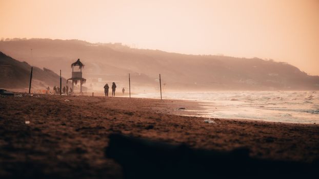A serene view of a misty beach with cliffs and ocean waves at sunrise.