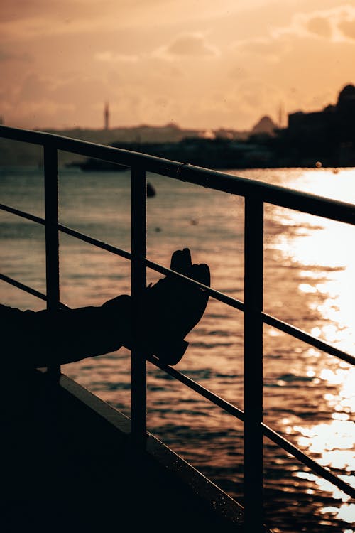 Silhouette of Person Legs near Water on Sunset