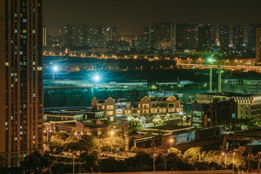 Aerial view of a city's illuminated skyline at night showcasing vibrant buildings and urban life.