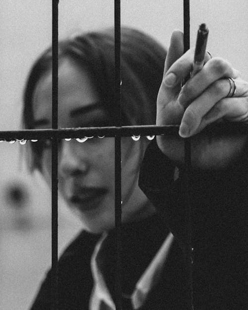 Woman Holding on Window Grill with Cigarette