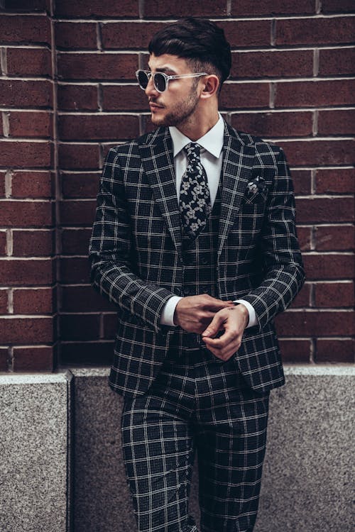 Free Man in Black and White Striped Blazer Standing Beside Red Brick Wall Stock Photo