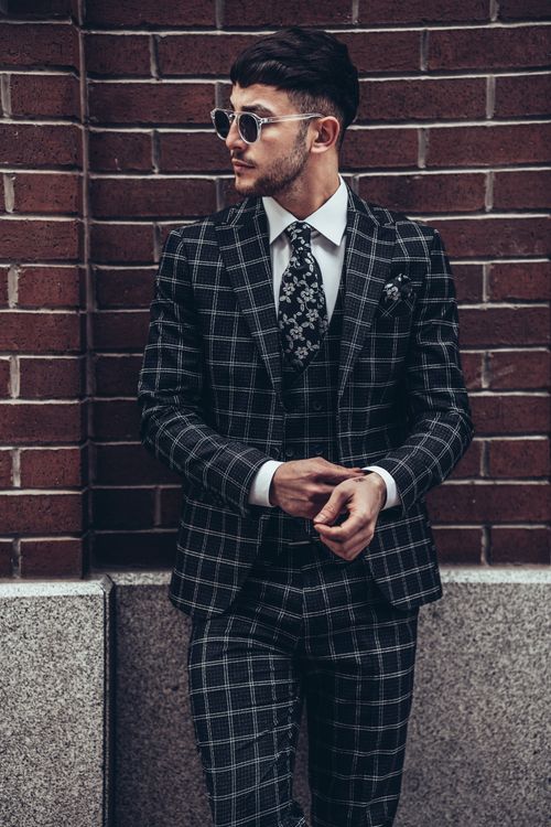 Free Man in plaid suit with sunglasses leaning against a brick wall in Istanbul. Stock Photo