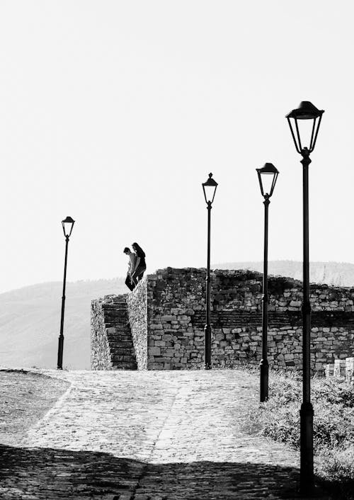 Street Lamps near Cobblestone Road and Couple Standing behind