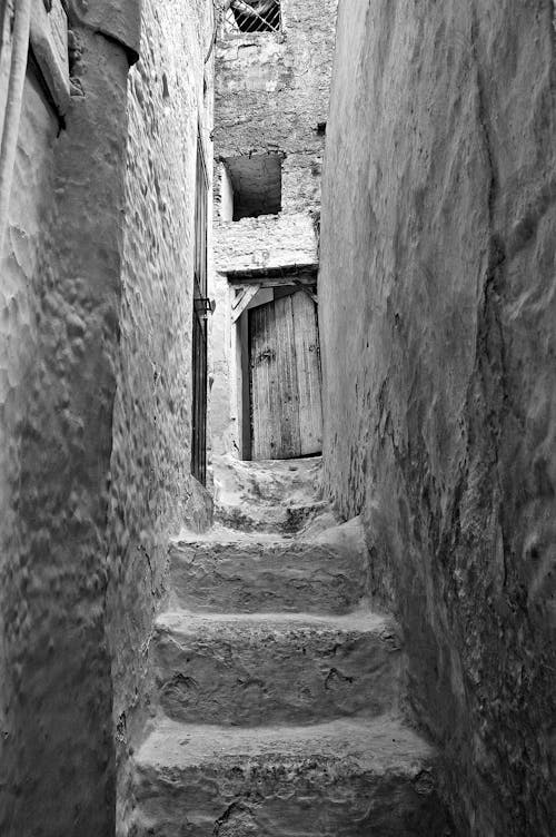 A Grayscale Photo of a Concrete Stairs Between Walls