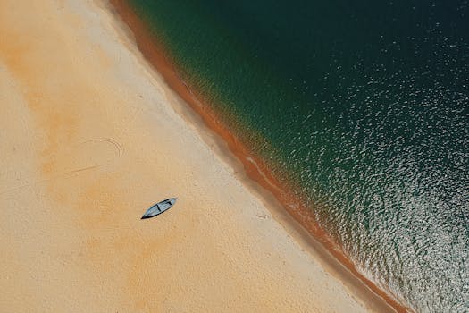 晴朗的天空下，波涛汹涌，一艘孤独的船停在金色的沙滩上