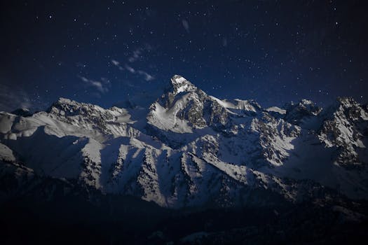 Breathtaking view of snow-capped mountains in Almaty under a star-filled night sky.