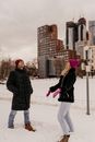 Woman in Black Coat and Pink Knit Cap Holding Umbrella Walking on Snow Covered Ground during