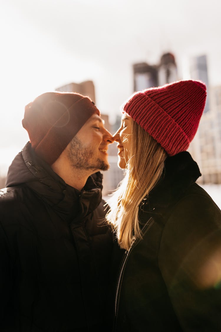 A Couple Standing Face To Face With Winter City In Background