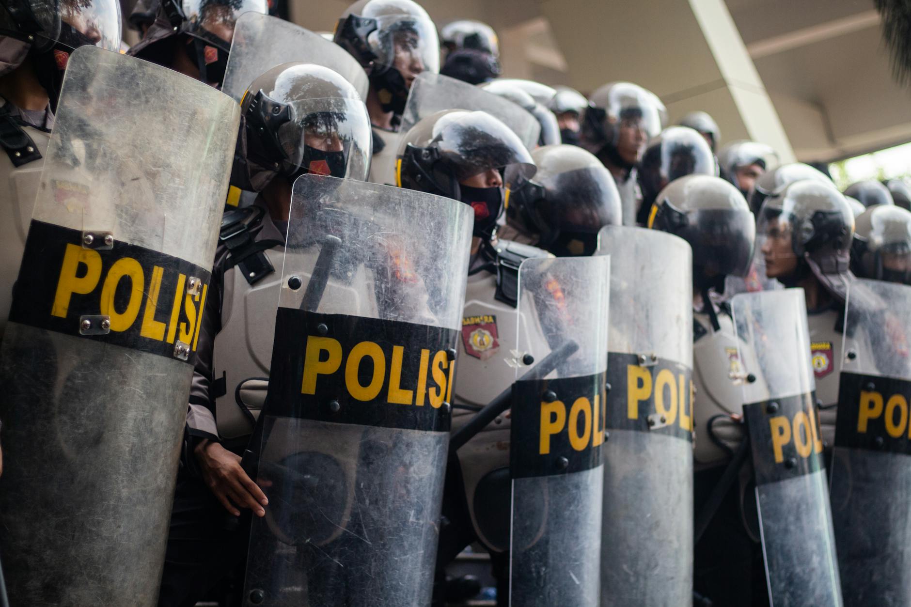 Indonesian policemen with shields in tactical formation during street protest.