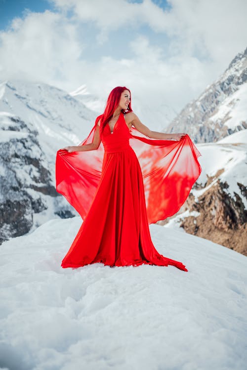 Redhead Woman Wearing Red Dress while Standing on Snow-Covered Ground
