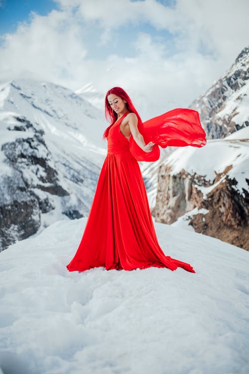Redhead Woman Wearing Red Dress while Standing on Snow-Covered Ground