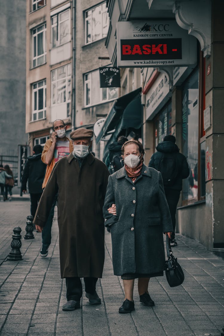 People Wearing Face Masks While Walking On The Sidewalk