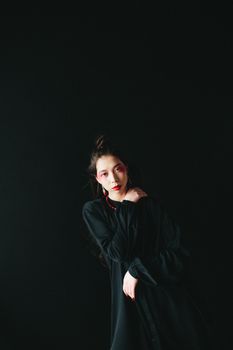 Stylish portrait of a woman in a black dress with dramatic lighting.