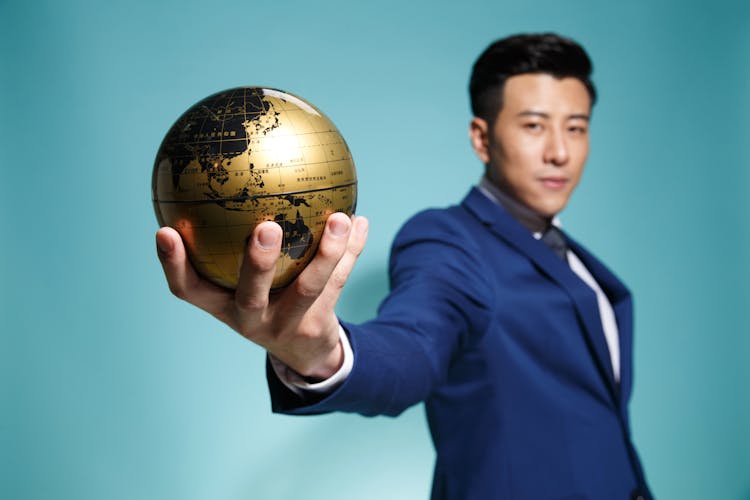 Man In Blue Suit Holding A Globe