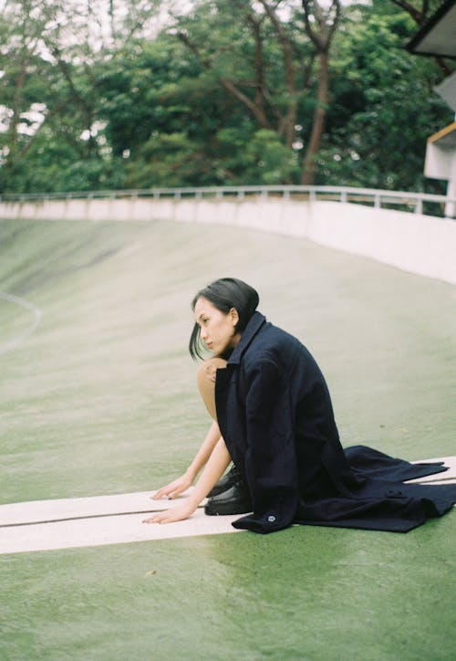 Woman in a Coat Crouching on the Grass