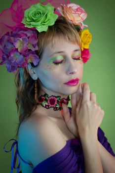 Vibrant portrait of a woman adorned with colorful floral headpiece against a green background.