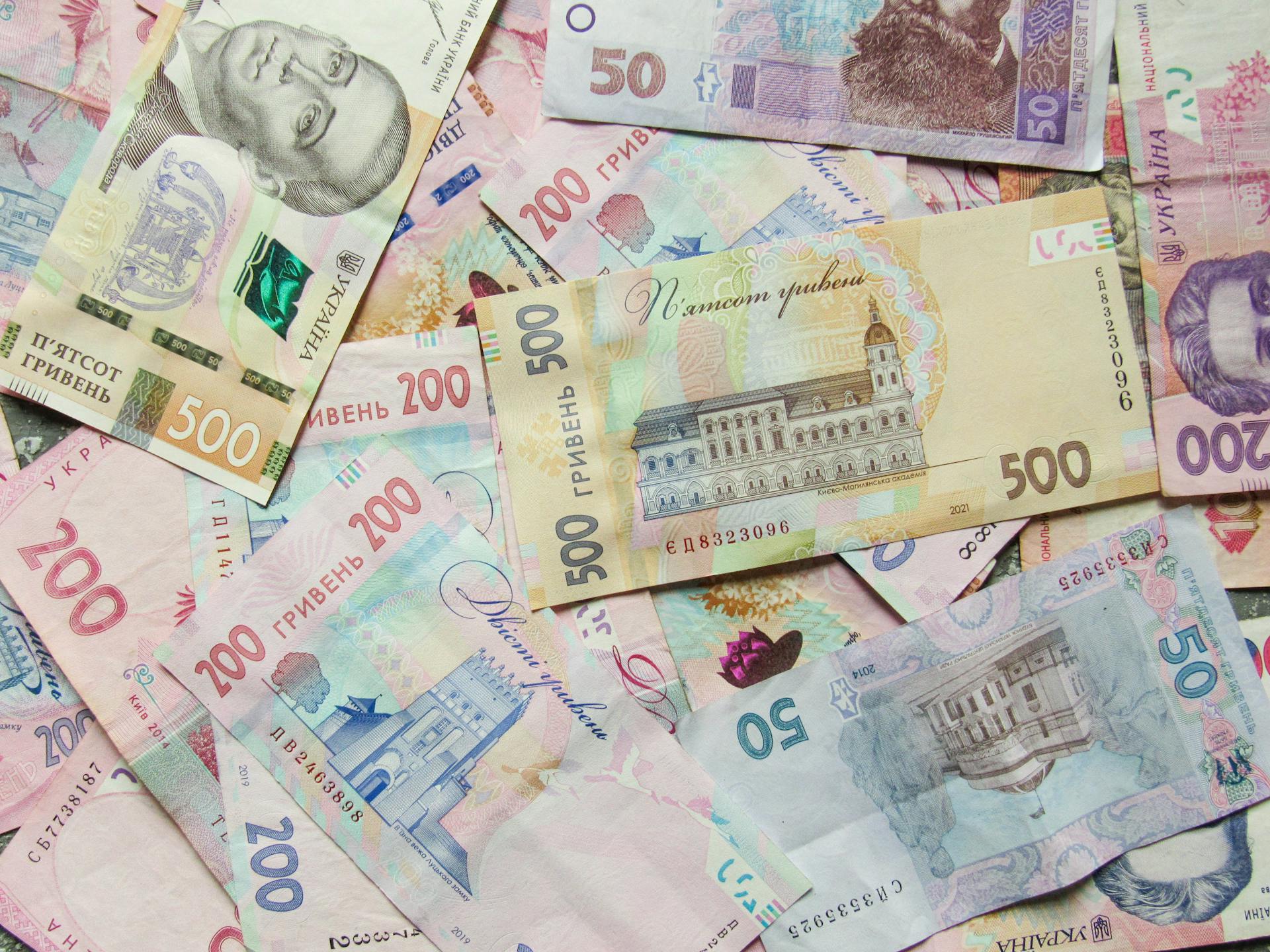 Close-up shot of Ukrainian banknotes featuring various denominations and designs.