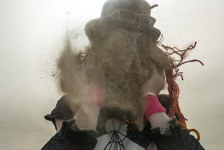 Spooky Photograph Of A Woman Putting On A Hat With Sand