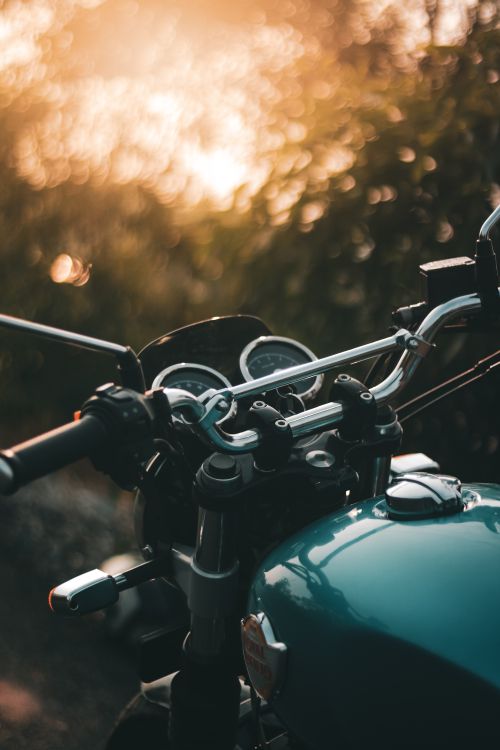 Free Vertical close-up of a motorcycle handlebar with sunset bokeh outdoors. Stock Photo