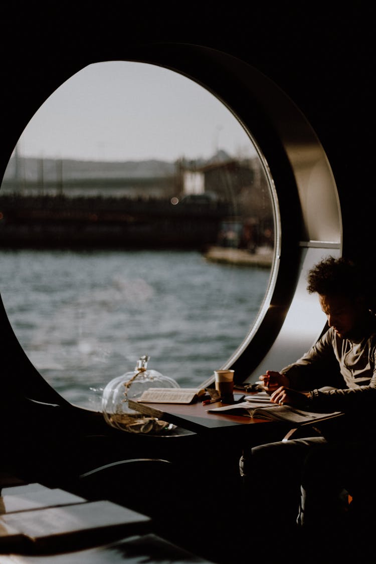 Man Sitting By A Window With A Sea View