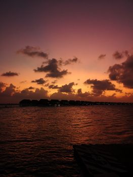 Stunning sunset view over the ocean with silhouette of water villas in Maldives. Perfect for tranquil and scenic themes.