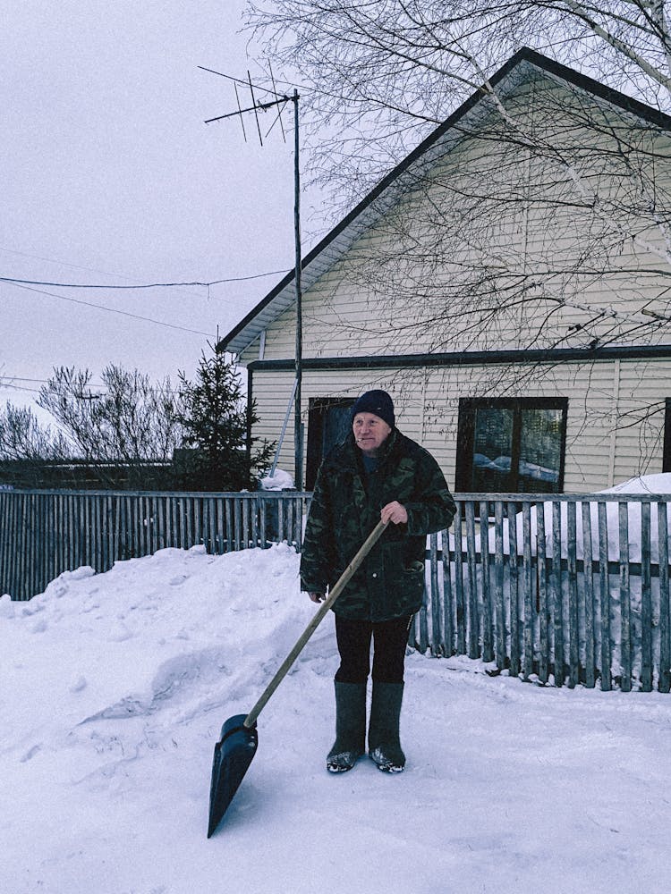 Man With A Shovel Standing On Snow