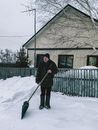 Elderly Man in Winter Coat Holding a Snow Shovel