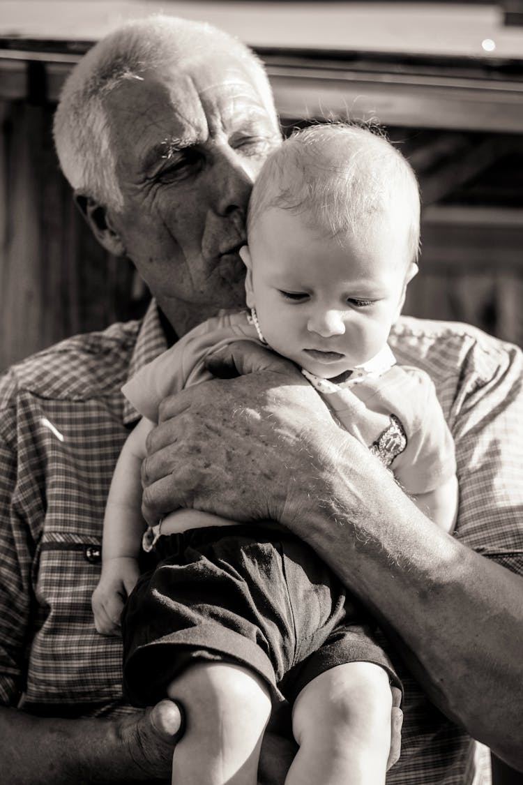 Grandfather Holding And Kissing His Grandson 