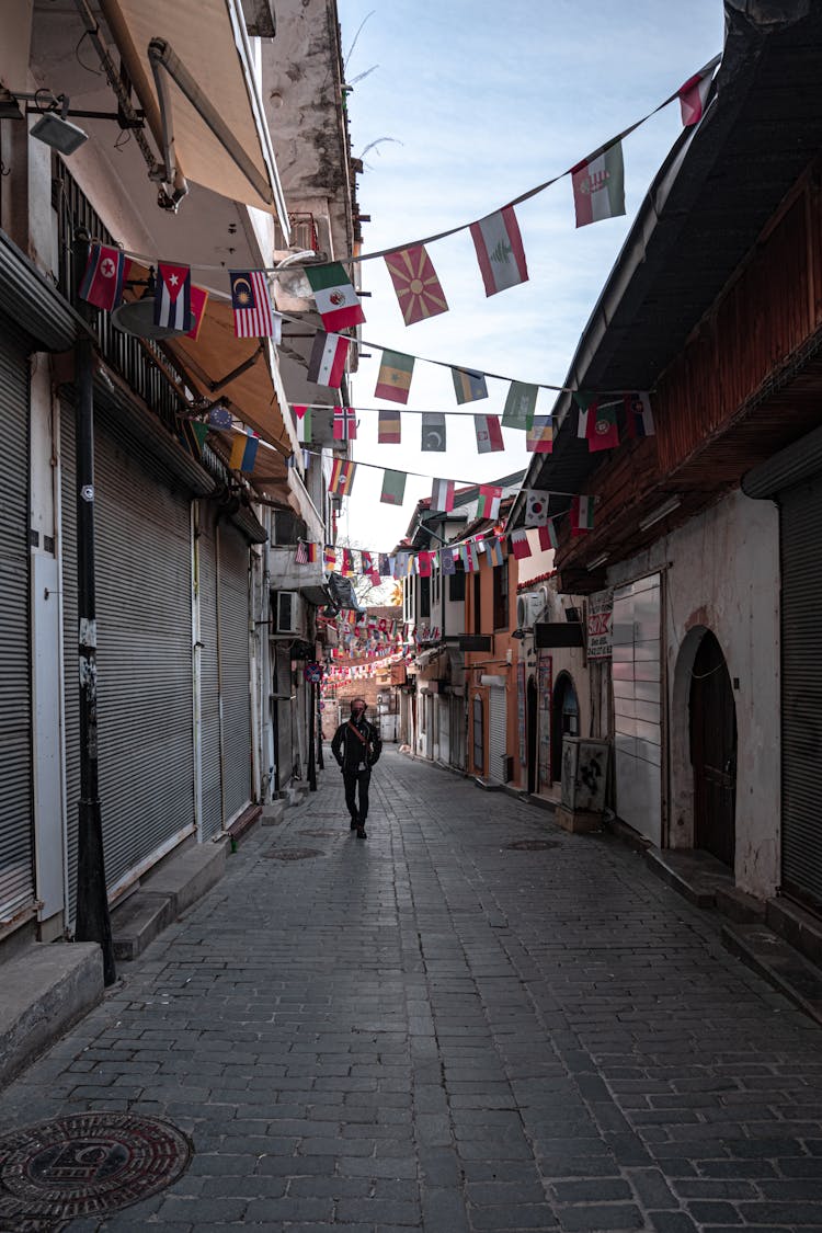 Man Walking City Alley With Hanging Flags