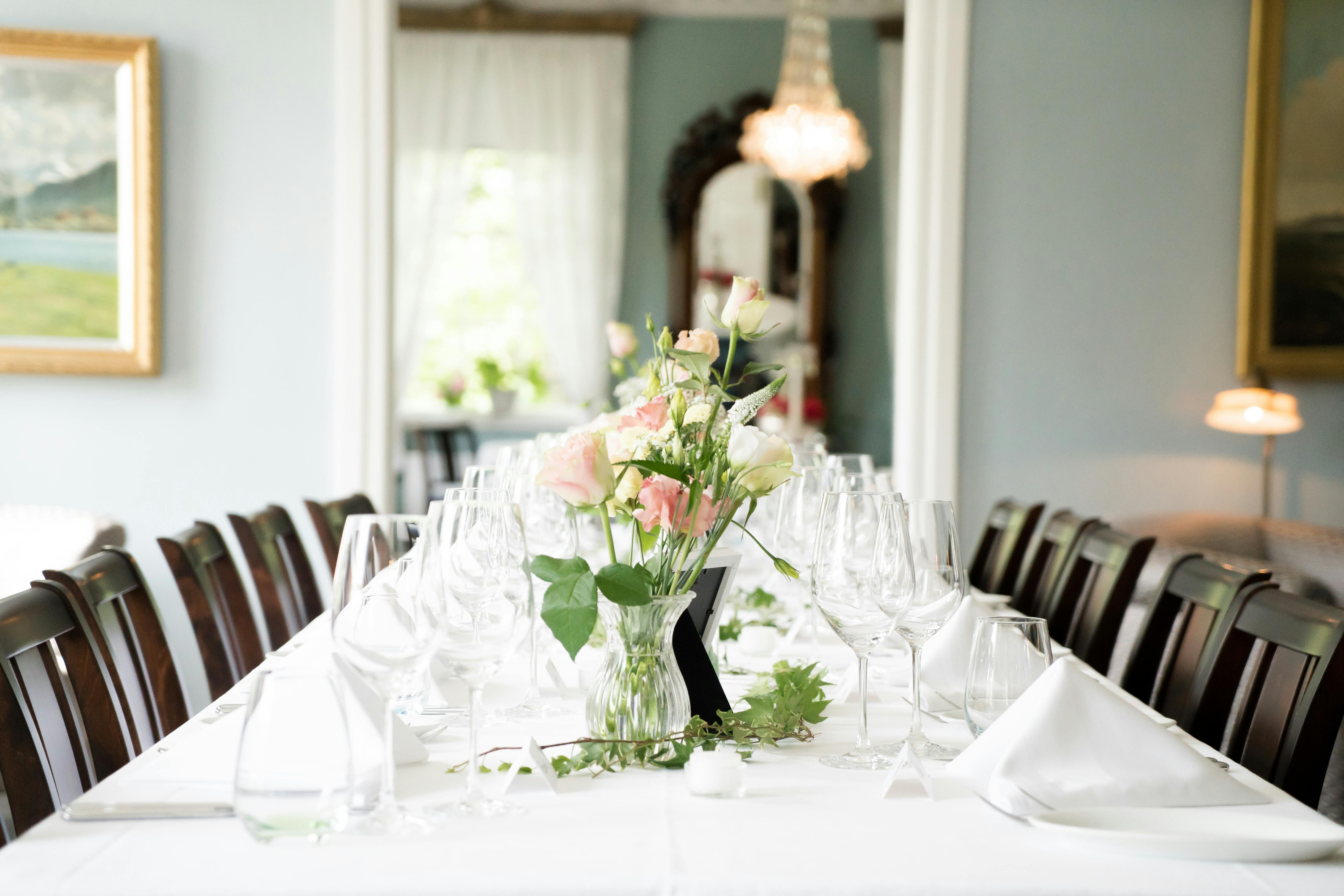 An elegantly set dining table with a floral centerpiece, captured in a bright, inviting room.