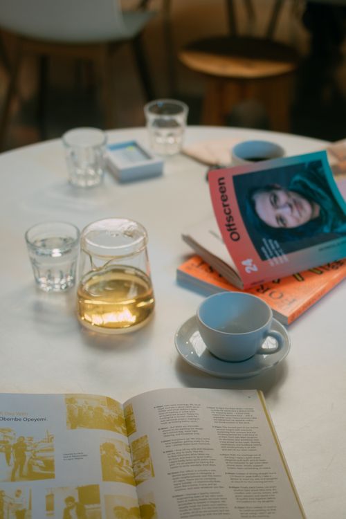 Free Warm table setting featuring a book, coffee cup, and magazines. Ideal for a cozy reading scene. Stock Photo