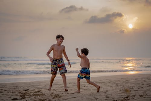 Two Boys Playing on the Sea Shore during Sunset