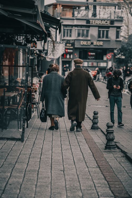 Free Back view of a couple strolling along a charming city pathway, capturing urban life. Stock Photo