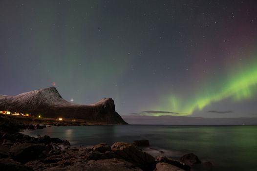 Stunning view of aurora borealis above a rocky shore in Viken, Norway during nighttime.