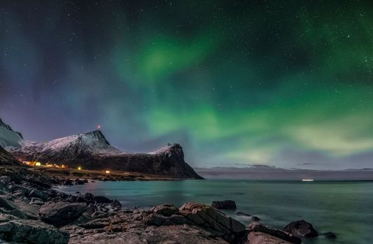 Brown Rocky Mountain Near Body of Water Under Green Sky