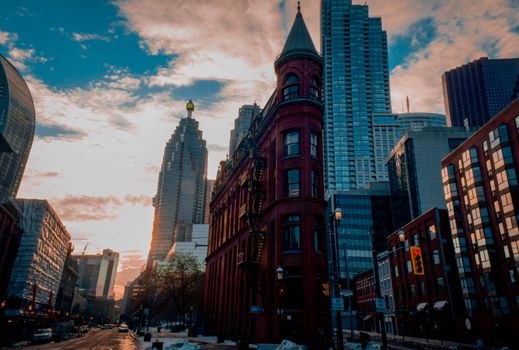 Beautiful winter sunset with Toronto's historic Flatiron Building surrounded by skyscrapers.