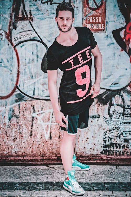 Man Wearing Black and Pink Tee 9-printed T-shirt in Front of Wall