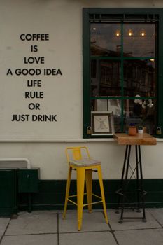 Inviting coffee shop scene with a motivational wall quote next to a window and yellow stool.