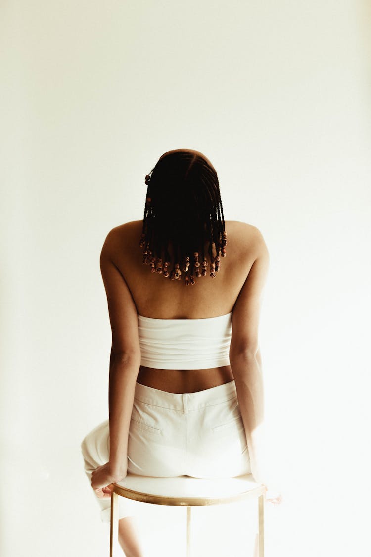 Back View Shot Of A Person Wearing White Tube Top And Pants While Sitting On A Chair