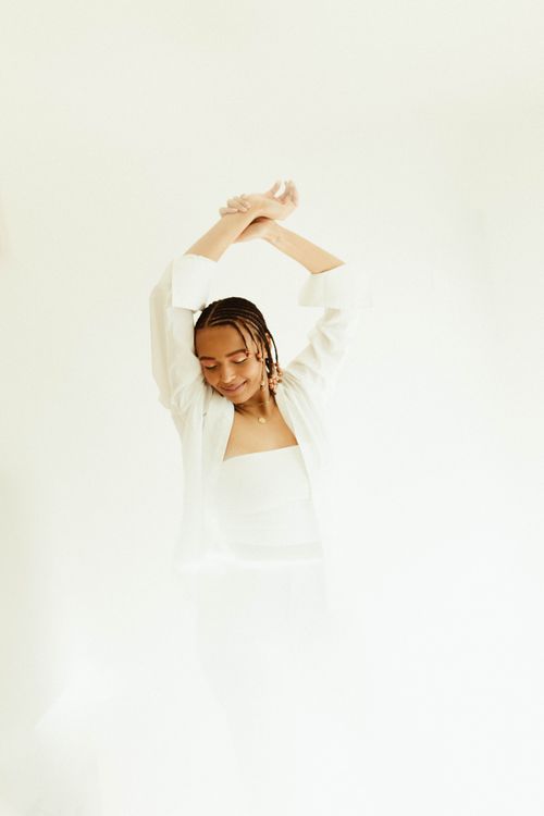 Free Elegant fashion portrait of a woman posing gracefully in a white outfit against a minimalist background. Stock Photo