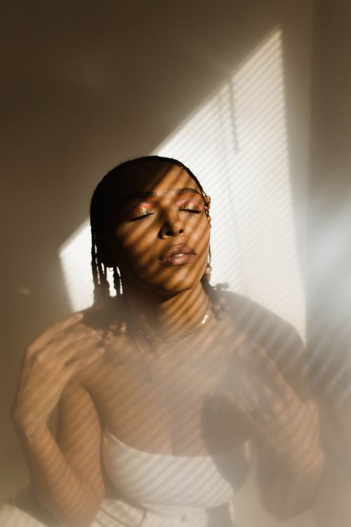 Free Portrait of a woman with cornrows in artistic shadows, eyes closed, in a studio setting. Stock Photo
