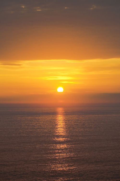 Free A serene golden sunset reflecting over the calm ocean, creating a peaceful seascape. Stock Photo