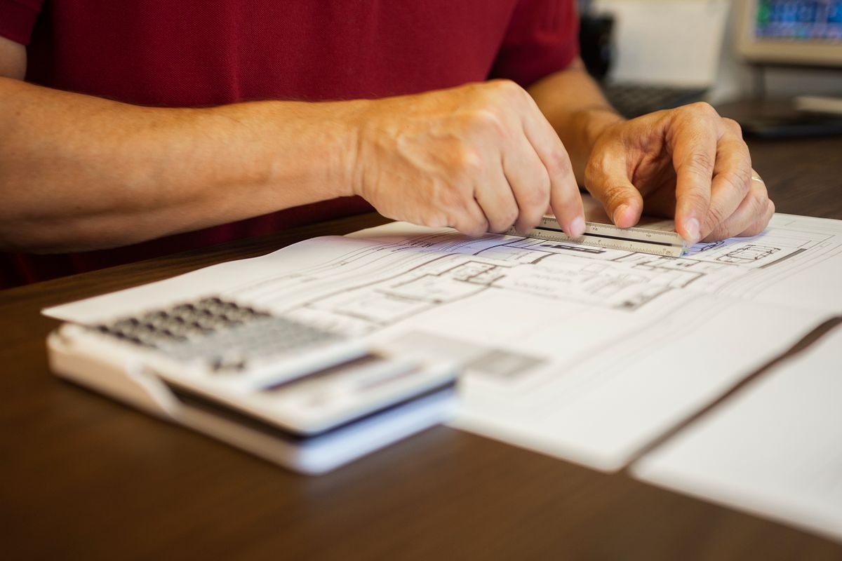 An engineer using a ruler to examine building blueprints