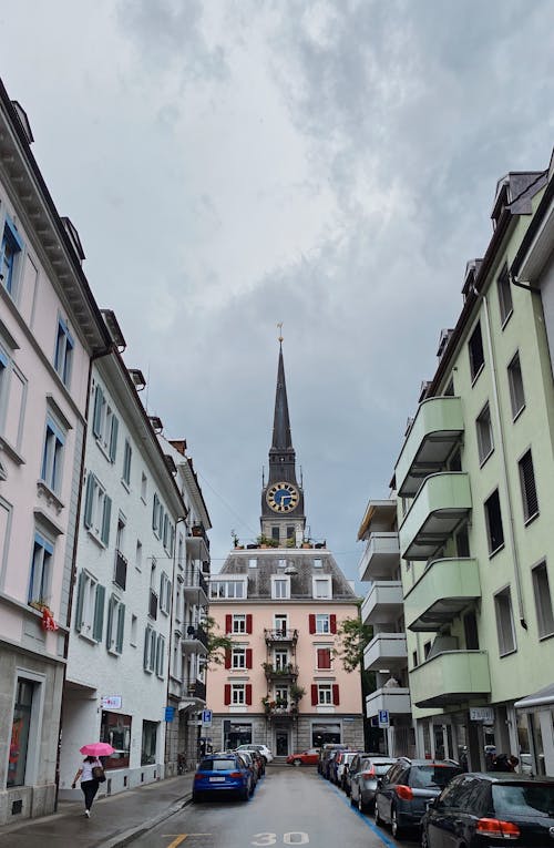 Cars Parked Near Concrete Buildings Under White Sky