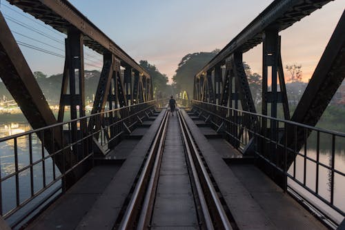 Woman Walking on Railway Bridge at Dusk