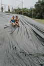 Happy Friends Holding Hands while  Sliding Together on a Black Tarp