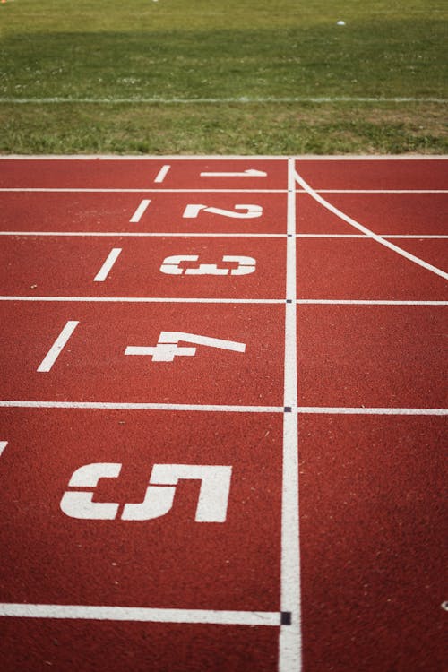 Free Close-up view of a red running track with numbered starting lanes, perfect for athletic themes. Stock Photo
