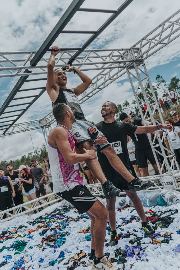 Men Helping Athlete Grab Monkey Bars