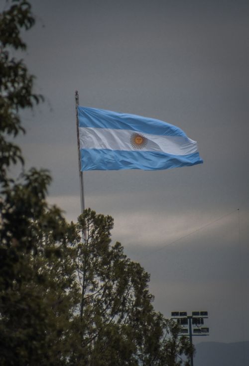 Free Argentinian flag flying against a gray sky in Salta, Argentina, symbolizing patriotism. Stock Photo
