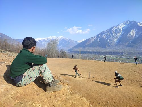 Free Children playing cricket against a backdrop of majestic snowcapped mountains in Srinagar. Stock Photo
